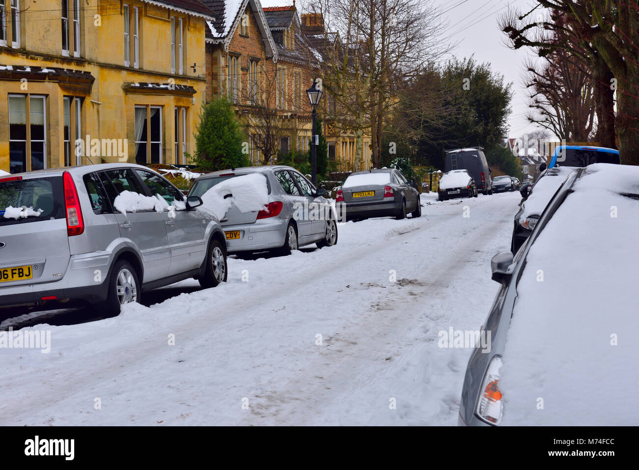 Luce neve che ricoprono le città strada residenziale con tracce di auto, Bristol, Regno Unito Foto Stock