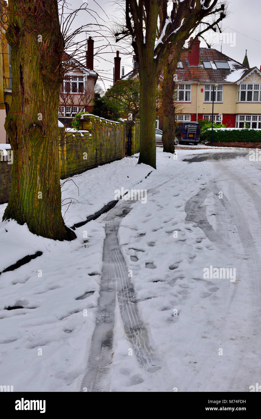 Luce neve che ricoprono le città strada residenziale con tracce di auto, Bristol, Regno Unito Foto Stock