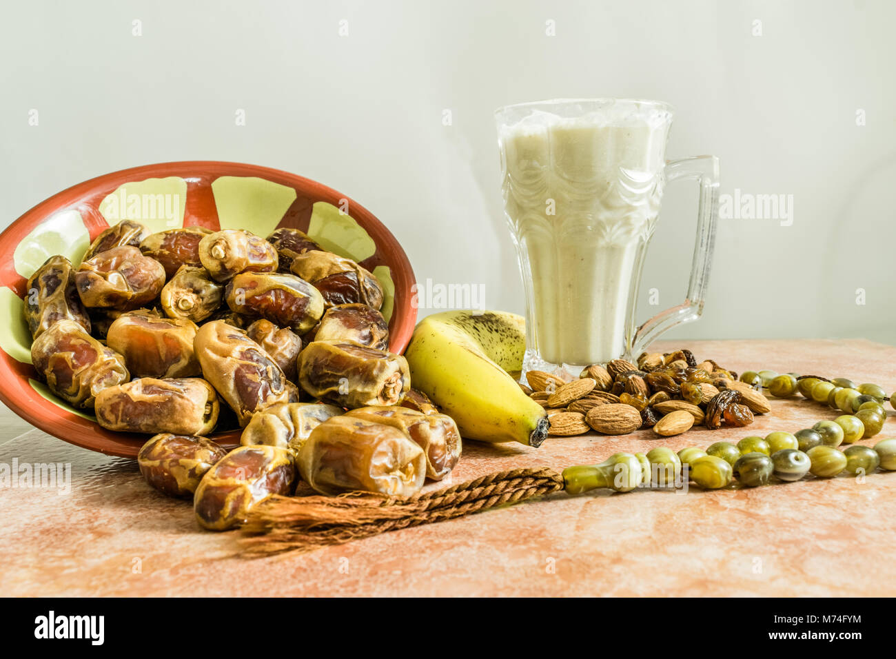 Un fresco bicchiere di banana milk shake con un sacco di date e di mandorle e un Tasbeeh religiosa mantenuta su un tavolo di marmo e pronto per aprire iftar nel santo m Foto Stock