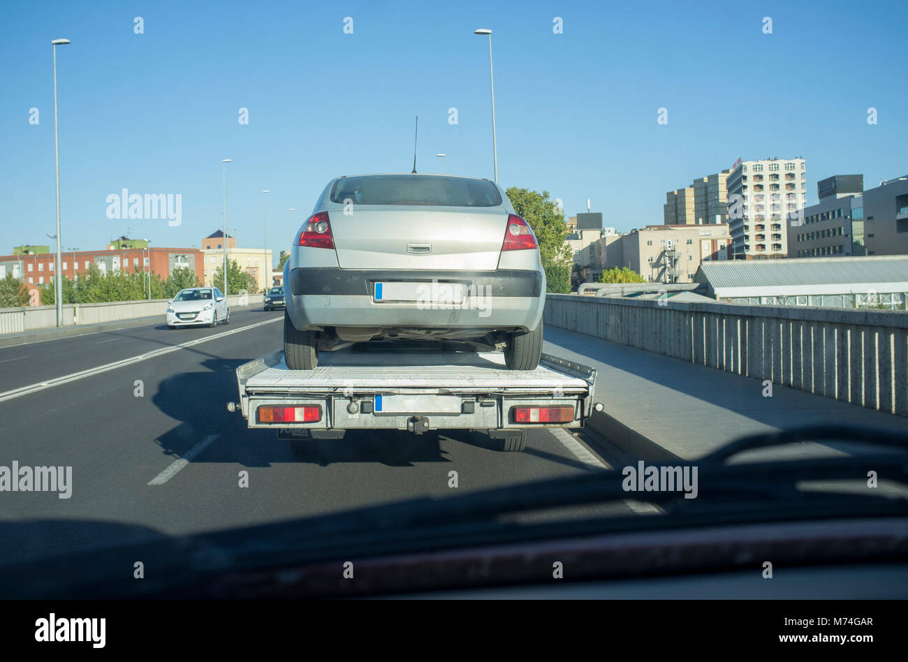 La guida su città dietro un lento carrello di traino. Vista dall'interno della vettura Foto Stock