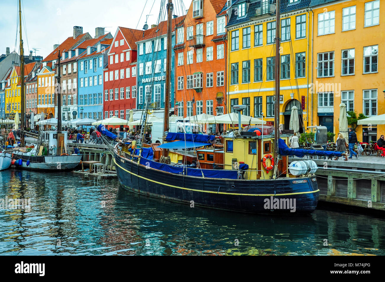 COPENHAGEN, Danimarca - 20 Aprile 2012 - colorata Nyhavn waterfront e il canale con le barche e le persone camminare e mangiare Foto Stock