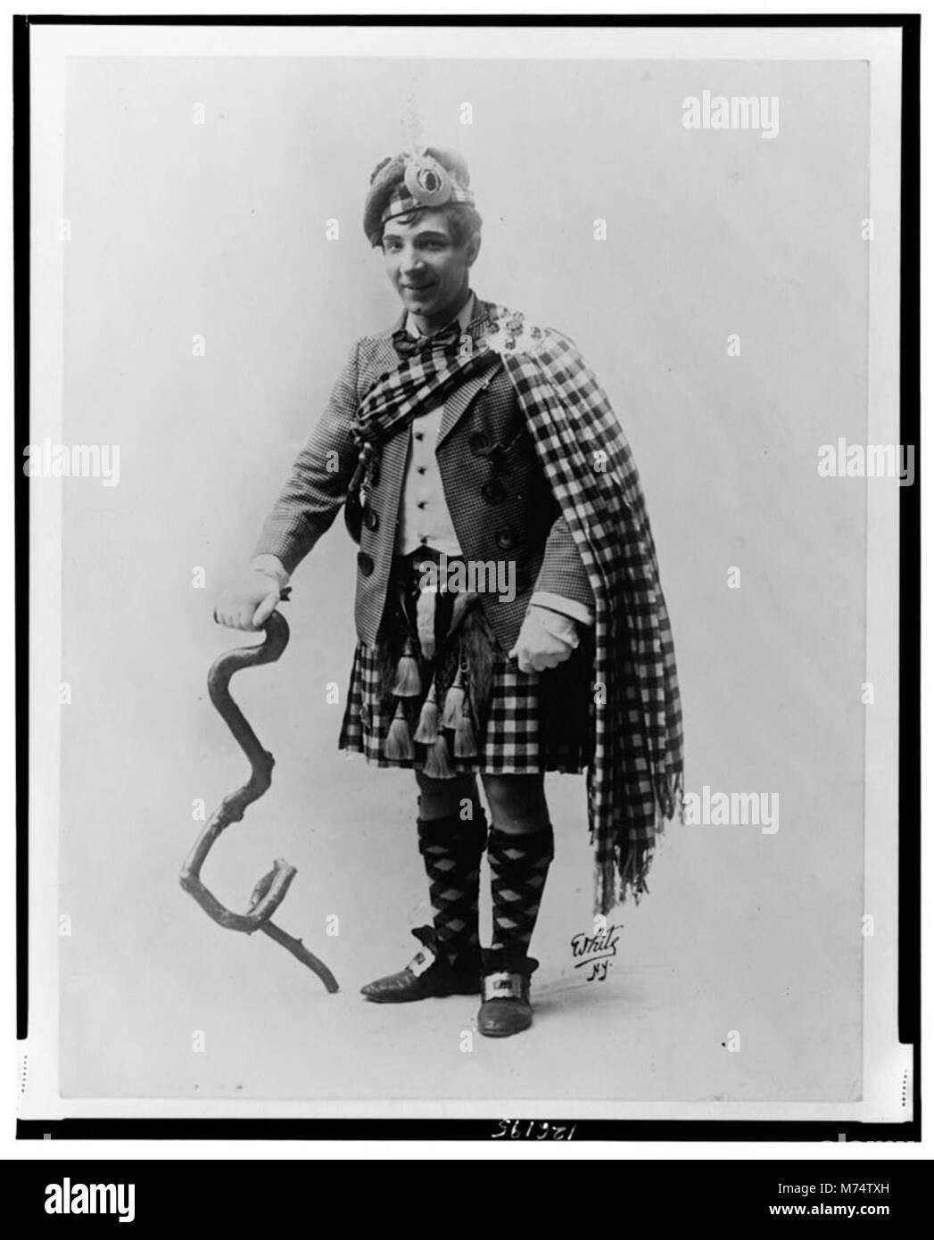 Questo ritratto a figura intera cattura Harry Lauder, un intrattenitore scozzese, in costume. Conosciuto per le sue esibizioni e la sua influenza sull'intrattenimento dei primi anni del XX secolo, l'immagine mette in risalto la sua carismatica personalità pubblica. Foto Stock