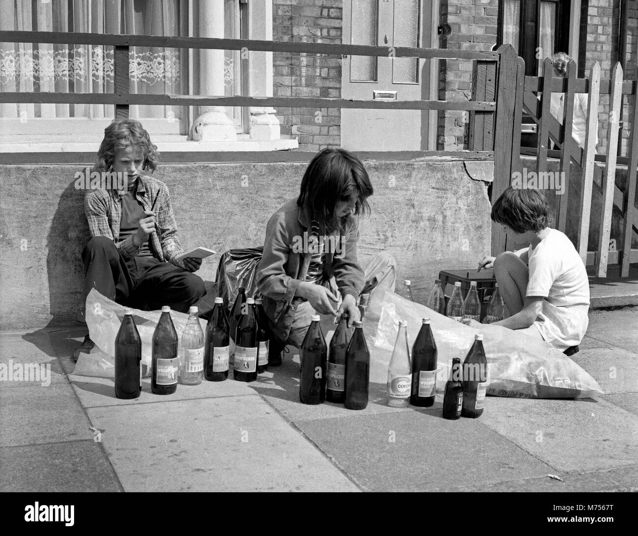 I ragazzi la raccolta di bottiglie in vetro per raccogliere il deposito indietro e apportare alcuni pocket money nel sud di Londra 1970 Foto Stock