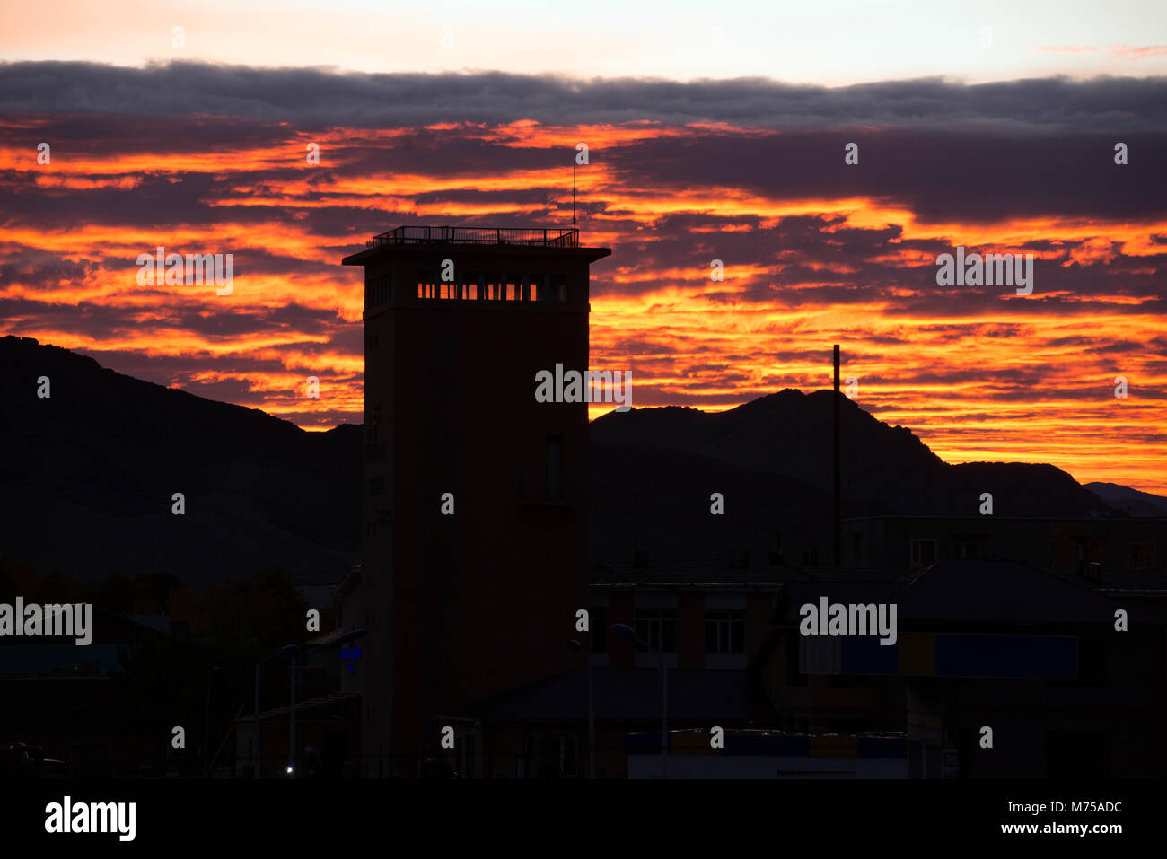 Uno degli edifici più alti della western città della Mongolia di Ölgii si stagliano contro il Rising Sun. Foto Stock