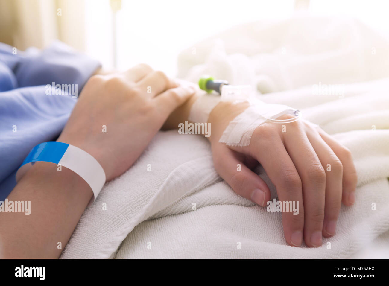 Paziente femmina di dormire sul letto del paziente in camera dopo un intervento chirurgico in ospedale con sunbeem. Foto Stock