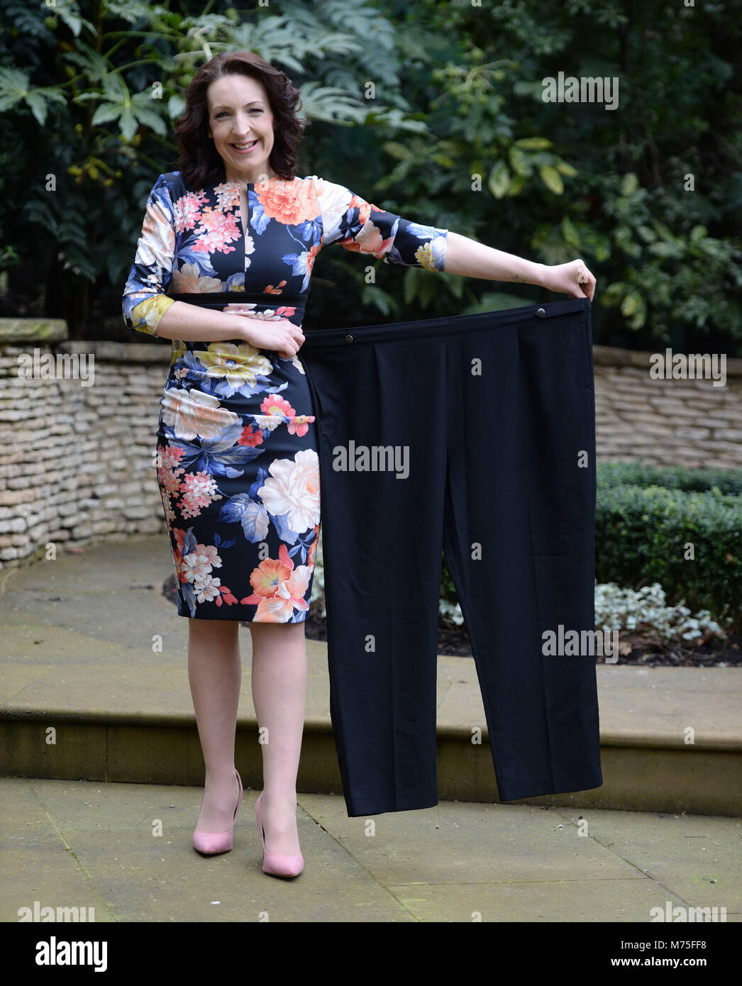 Laura Cosbie, 35, contiene una coppia di suoi vecchi pantaloni come ella è svelata come dimagrimento del mondo più snella dell'anno 2018 al Ritz di Londra centrale. Foto Stock