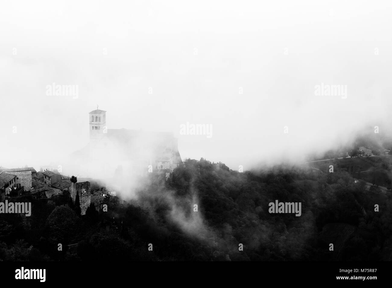 Vista di San Francesco chiesa papale in Assisi (Umbria, Italia) nel mezzo di sollevamento di nebbia di mattina Foto Stock