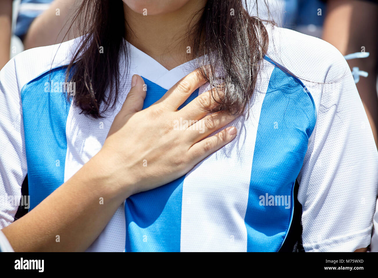 Il calcio argentino sostenitore tenendo la mano sul cuore a corrispondere, close-up Foto Stock