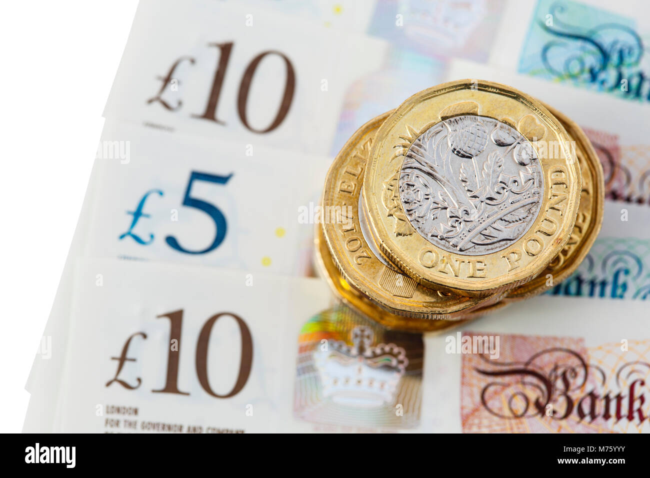 Pila di British 12 lati una libbra di monete soldi sterline sul nuovo polimero £10, £5 note GBP close-up su uno sfondo bianco. Inghilterra Regno Unito Gran Bretagna Foto Stock