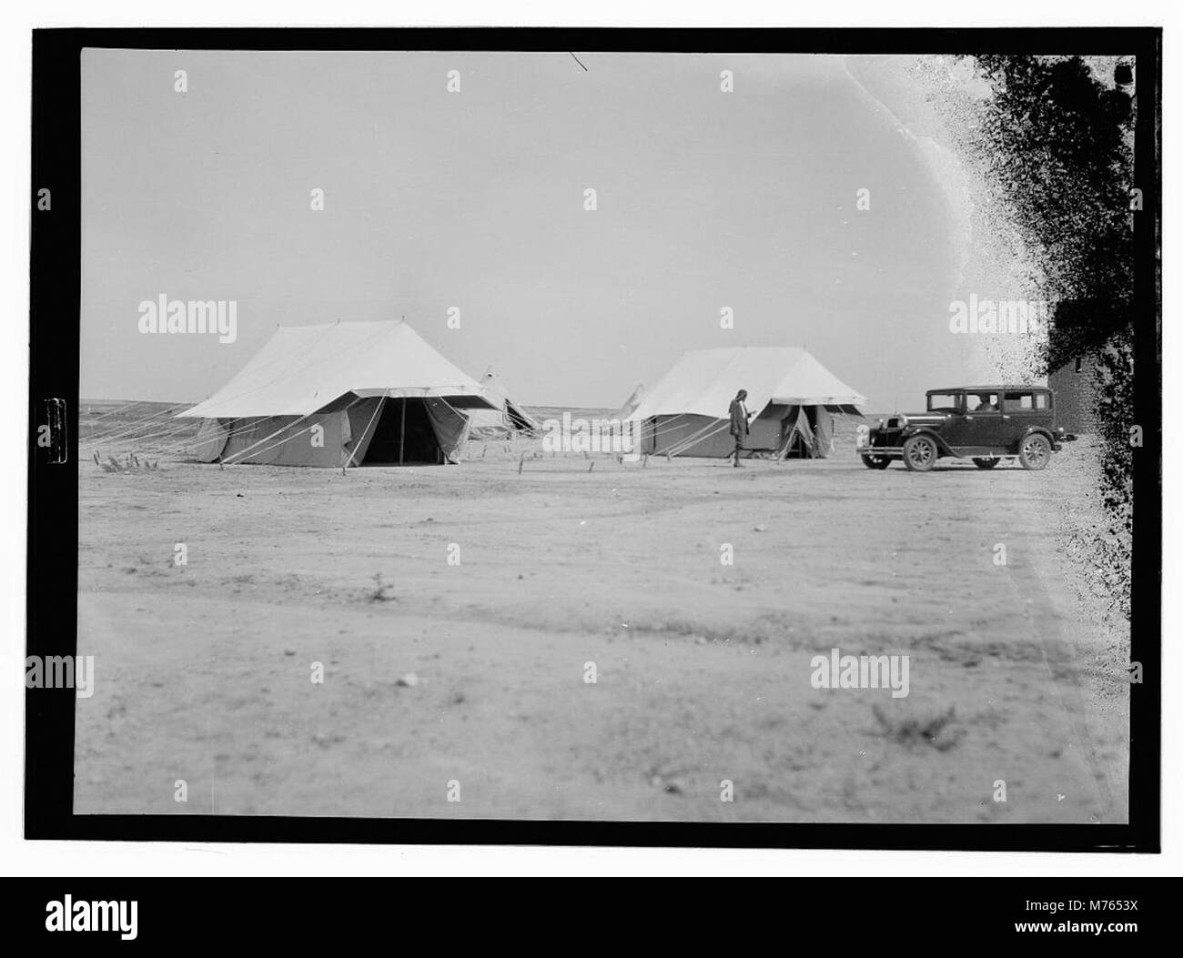 Un'immagine di un campo di lavoratori di locuste, che cattura le abitazioni temporanee e l'ambiente in cui i lavoratori soggiornavano durante gli sforzi per controllare le infestazioni di locuste. I lavoratori facevano parte di iniziative di gestione di parassiti agricoli su larga scala per proteggere le colture e i mezzi di sussistenza dagli sciami di carrube. Foto Stock