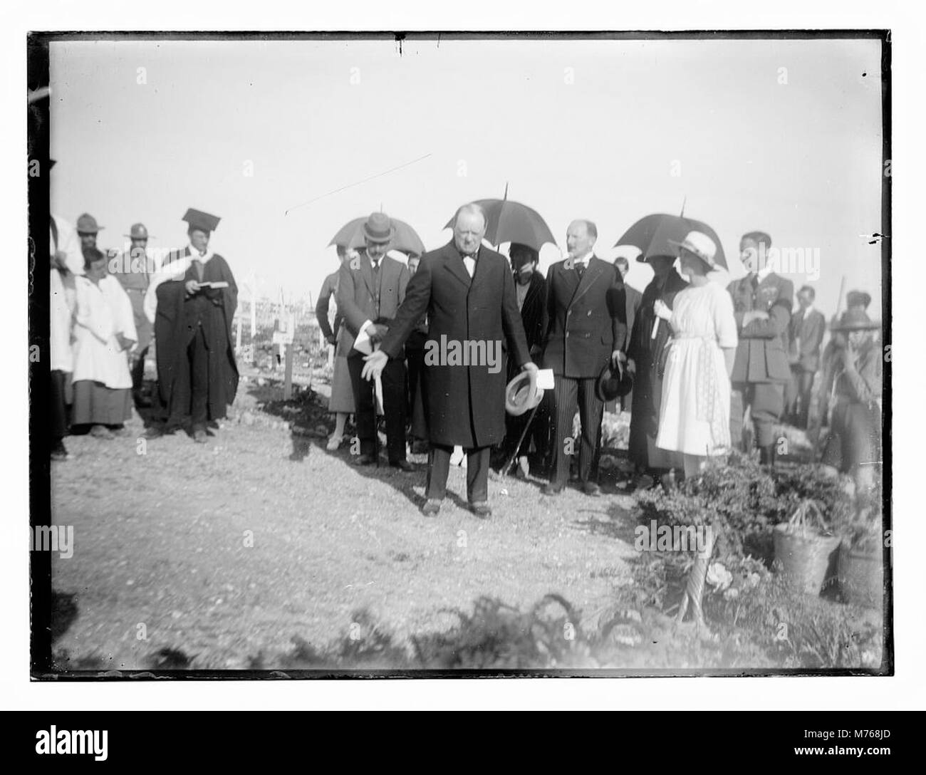 Questa immagine raffigura uomini e donne, probabilmente tra cui Winston Churchill e Herbert Samuel, in un cimitero militare con il clero cristiano. Rappresenta la solennità e il rispetto dei caduti durante la guerra. Foto Stock