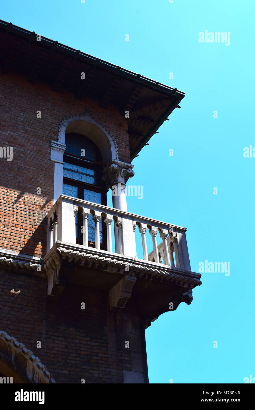 Una finestra sul Canal Grande Venezia Italia con balcone in ombra profonda contro un cielo blu chiaro. Foto Stock