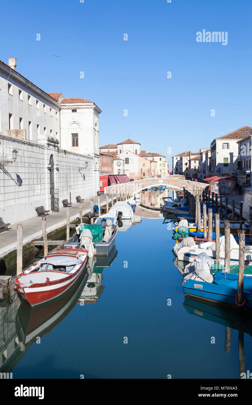 Barche colorate e riflessioni sulla vena Canal, Chioggia, Venezia, Italia guardando verso il mercato del pesce e la Chiesa di Sant Andrea Foto Stock