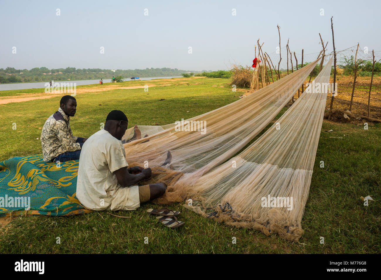 I pescatori a riparare le reti da pesca sul fiume Niger, Niamey, Niger, Africa Foto Stock