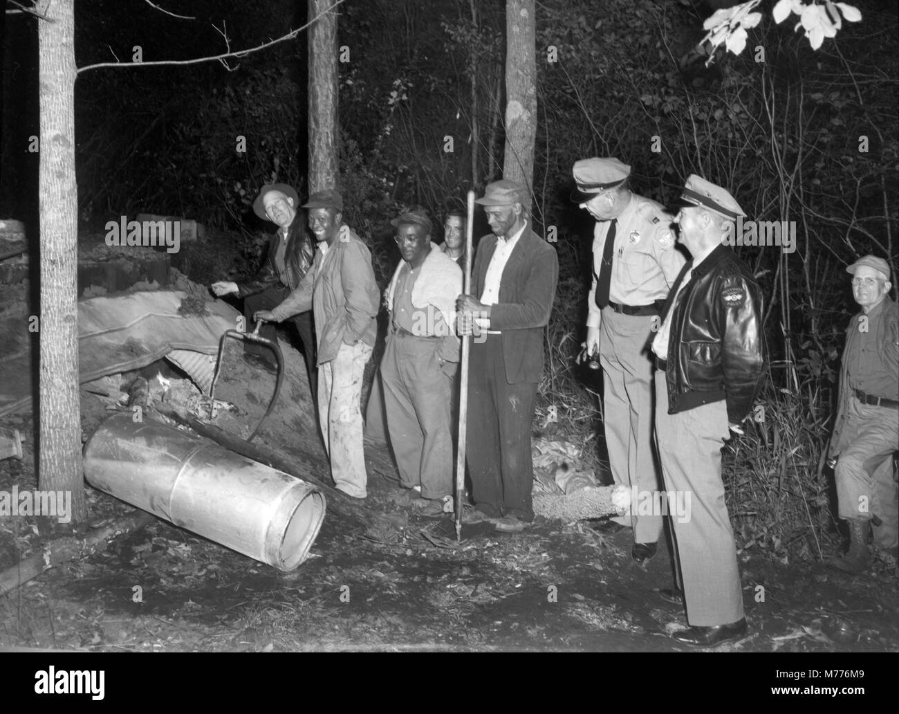 Dei funzionari incaricati di applicare la legge indagare sulla scena di un illecito di meandri moonshine ancora in Georgia rurale, ca. 1955. Foto Stock