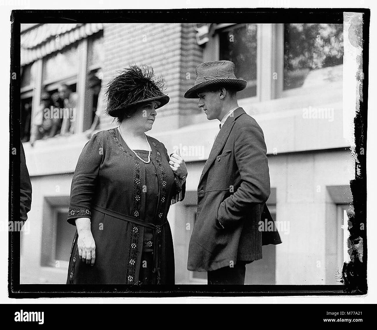 Una fotografia di una donna e di un uomo non identificati fuori da un edificio cittadino. L'immagine fornisce uno sguardo sull'abbigliamento e sulla vita urbana dei primi anni del XX secolo durante questo periodo. Foto Stock