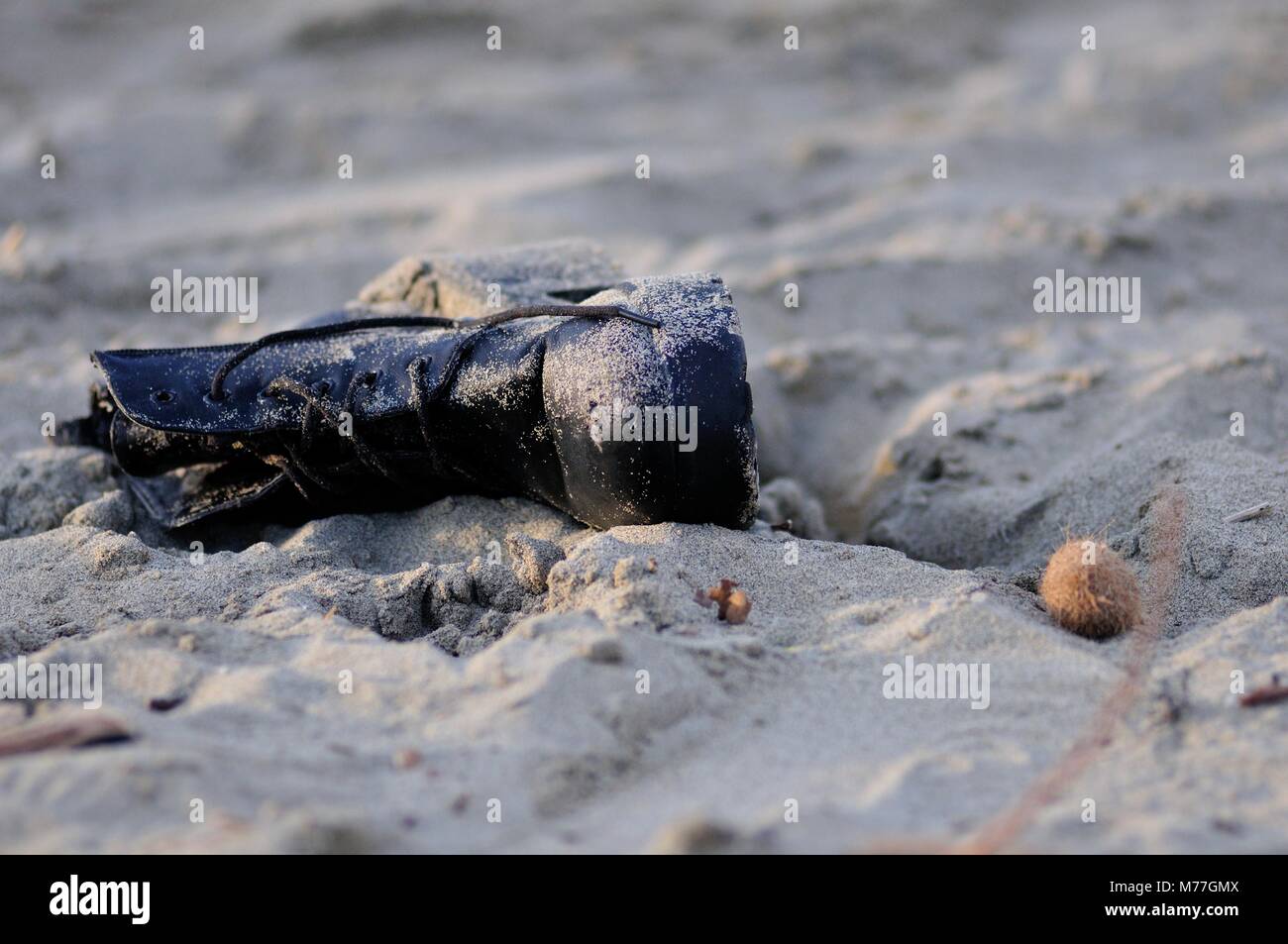 Scarpone in pelle nera abbandonati sulla spiaggia Foto Stock