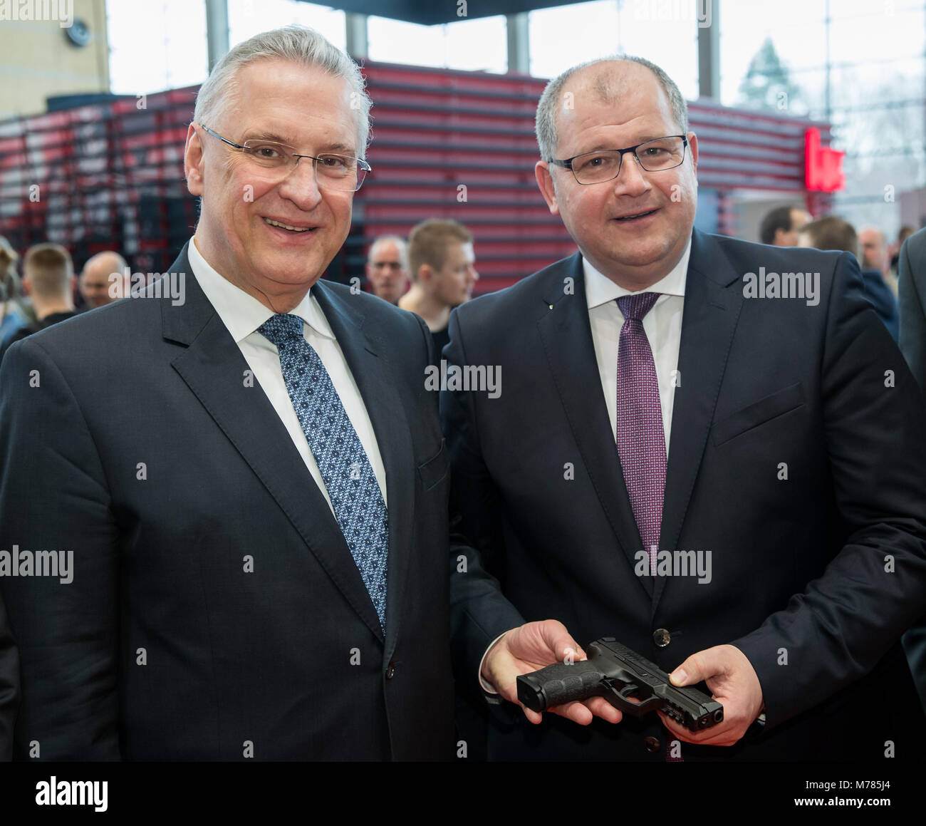 09 marzo 2018, Germania, Norimberga: Joachim Herrmann (L) di dell'Unione sociale cristiana (CSU), il ministro degli Interni della Baviera, e Wolfgang Hesse, amministratore unico di Heckler & Koch AG, in piedi con il modulo SFP9-TR (calibro 9x19) servizio pistola della polizia bavarese durante l'IWA OutdoorClassics trade show per caccia e tiro sport, attrezzature per attività all'aperto e per civili e ufficiali di applicazioni di sicurezza. Foto: Daniel Karmann/dpa Foto Stock
