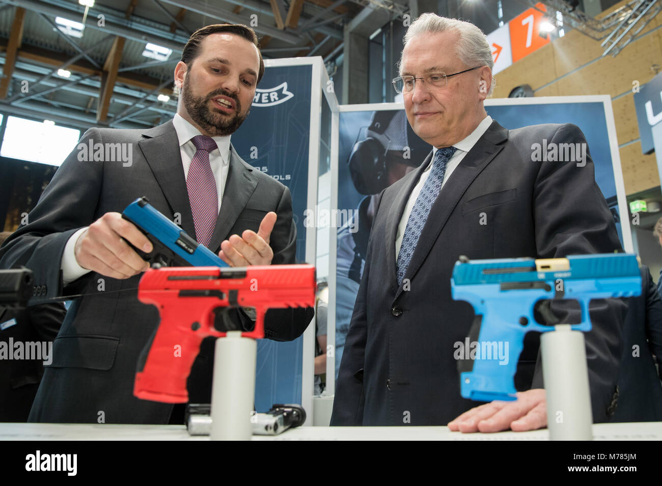 09 marzo 2018, Germania, Norimberga: Eyck Pflaumer (L), il CEO del produttore di armi Umarex, presentando una pistola di servizio della polizia di Joachim Herrmann del cristiano sociale europea (CSU), il ministro degli Interni della Baviera, durante l'IWA OutdoorClassics trade show per caccia e tiro sport, attrezzature per attività all'aperto e per civili e ufficiali di applicazioni di sicurezza. Foto: Daniel Karmann/dpa Foto Stock