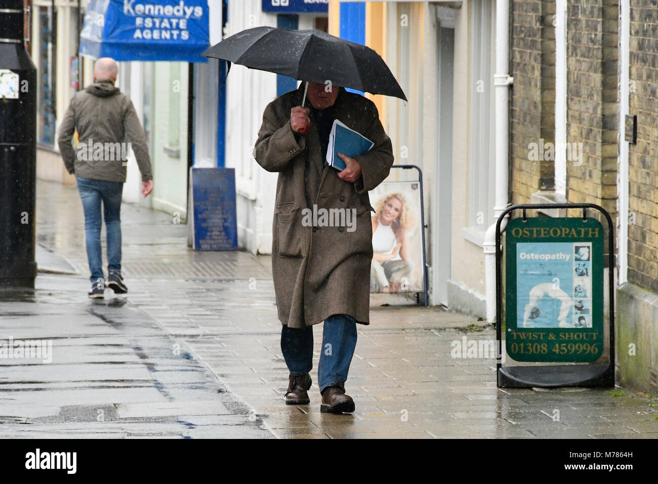 Bridport, Dorset, Regno Unito. Il 9 marzo 2018. Regno Unito Meteo. Gli amanti dello shopping in Heavy Rain con ombrelloni a città mercato di Bridport nel Dorset. Credito Foto: Graham Hunt/Alamy Live News. Foto Stock