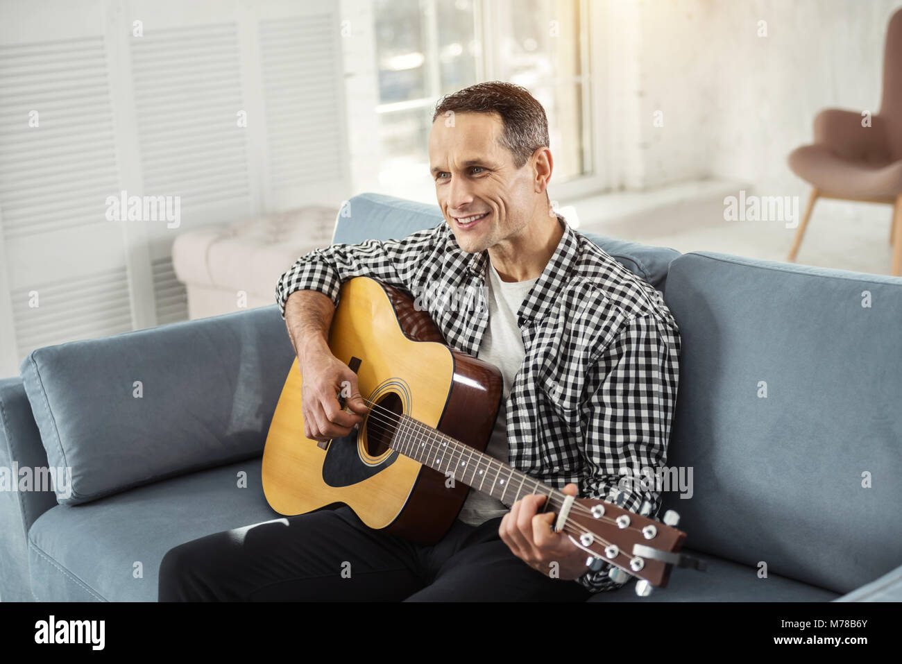 Uomo esuberante e rilassante a suonare la chitarra Foto Stock