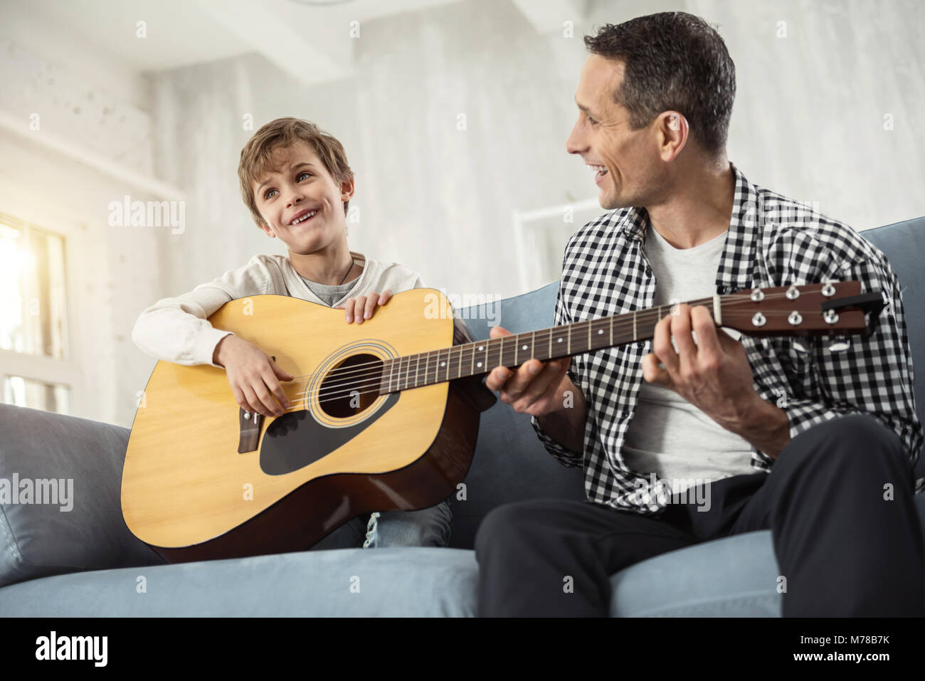 Ragazzo allegro e suo padre a suonare la chitarra Foto Stock