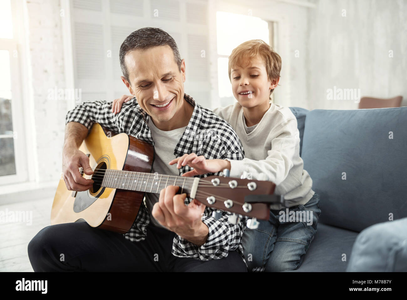 Padre di avviso a suonare la chitarra per suo figlio Foto Stock