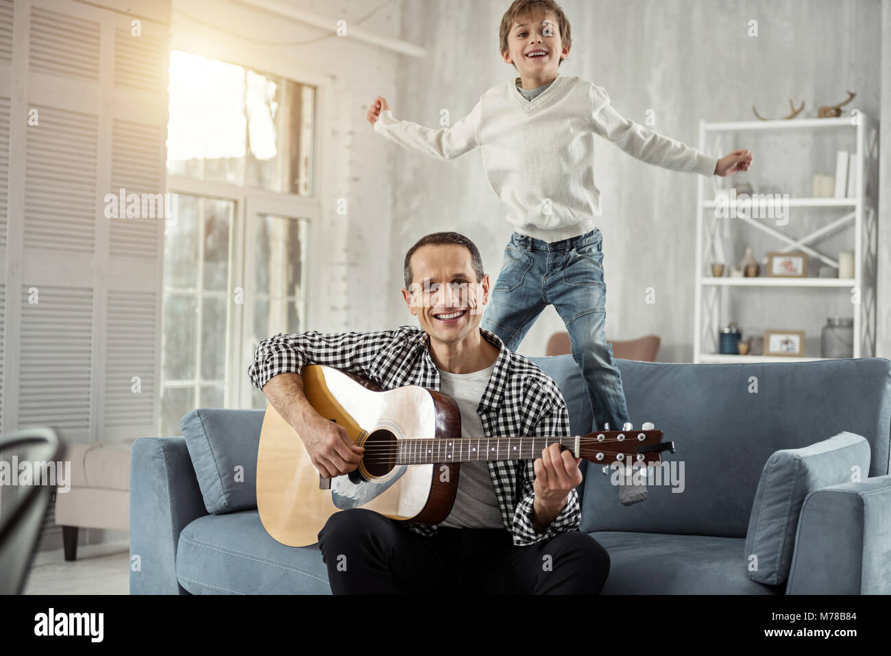 Esuberante daddy a suonare la chitarra per suo figlio Foto Stock