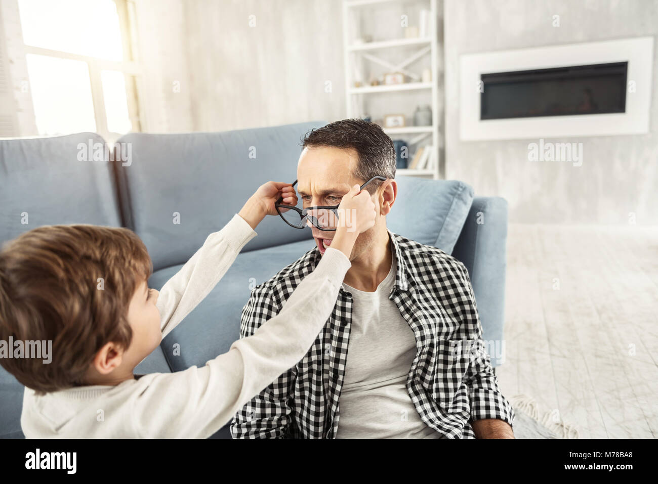 Biondo ragazzo mettendo grandi bicchieri sul suo papà Foto Stock