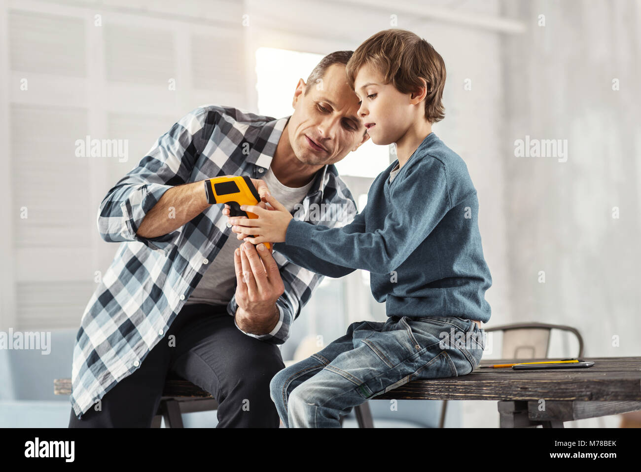 Daddy gravi che mostra i suoi strumenti a suo figlio Foto Stock
