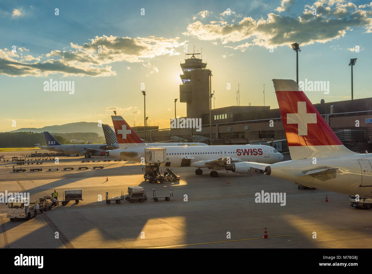 L'aeroporto di Zurigo al tramonto con aerei parcheggiati (Swiss Airlines in primo piano) e la torre di controllo. Foto Stock
