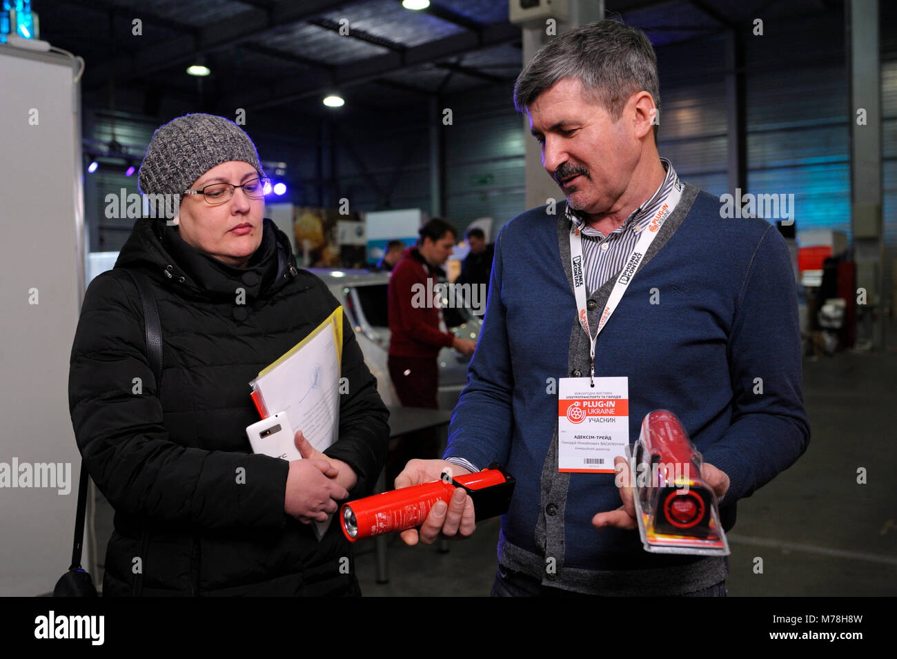 Sales Manager tenendo gli estintori aerosol nelle mani di spiegare a un cliente di vantaggi per le auto.Marzo 2, 2018. Kiev Expo Center. A Kiev, Ucraina Foto Stock
