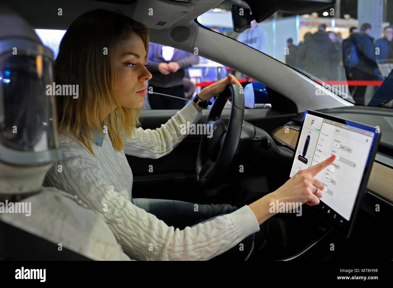 Driver per manipolare un monitor touch screen in cabina di una nuova auto elettrica Tesla. Mostra PLUG-IN UCRAINA NEL 2018. Il 2 marzo 2018. A Kiev, Ucraina Foto Stock