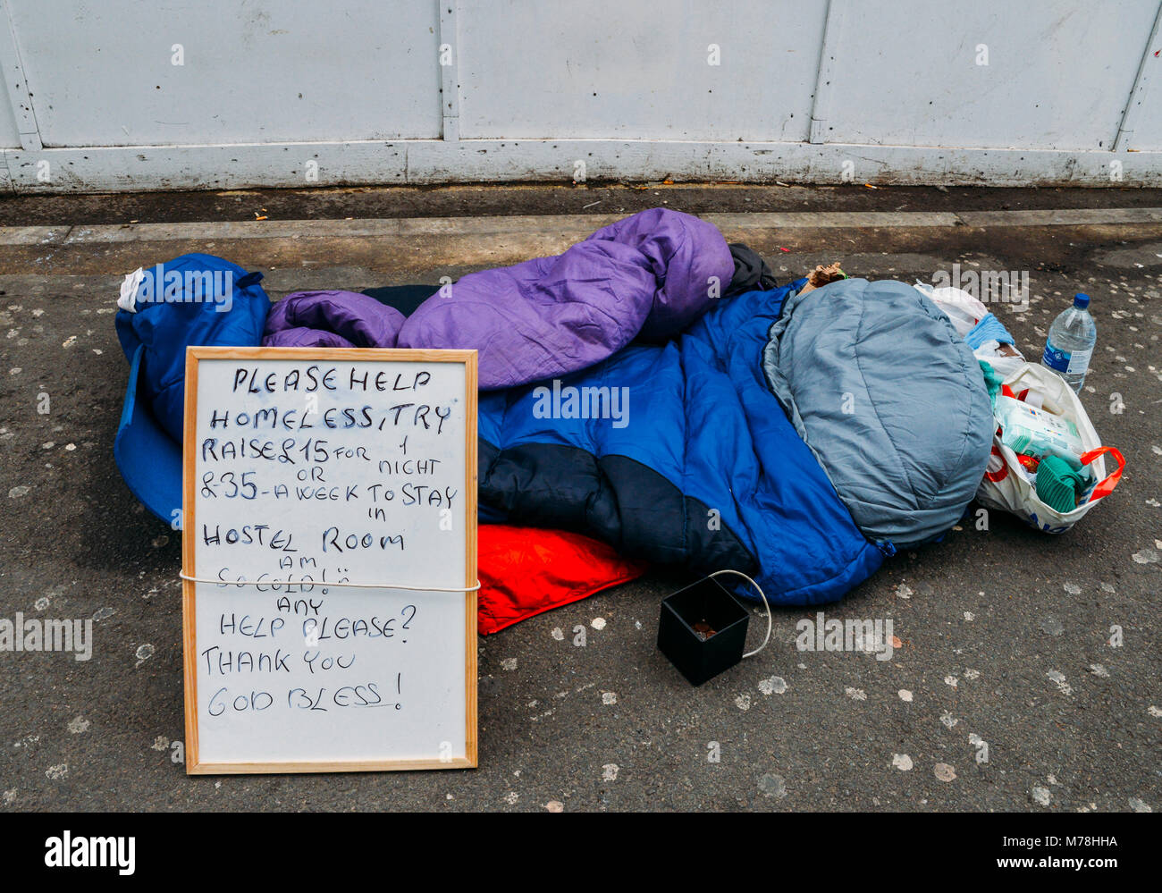 Londra, UK Mar 6, 2018: Segno sul lato del marciapiede della persona senza dimora con sacco a pelo, cibo e cup per cambiare - Concetto di austerità, catturato in Londra Foto Stock