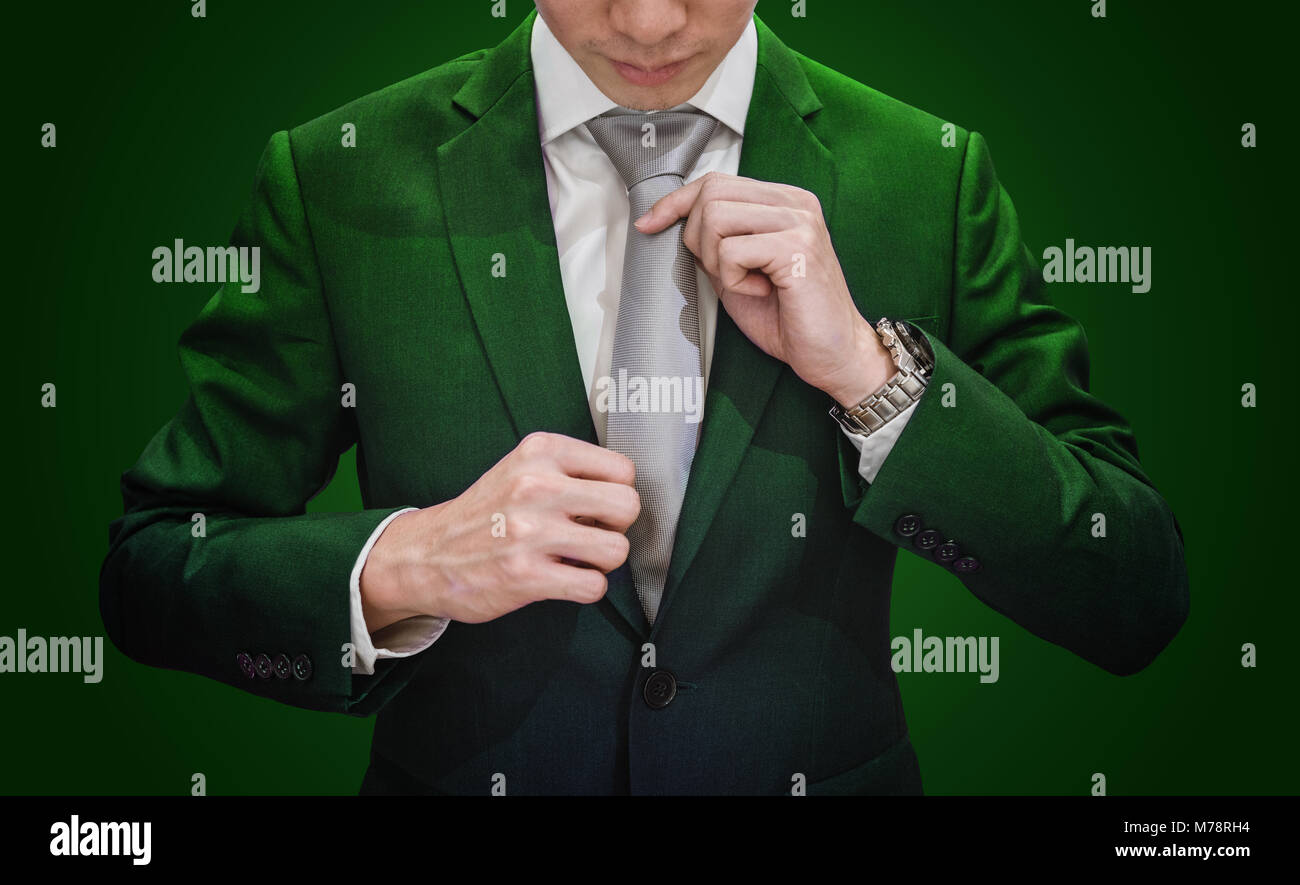 Imprenditore in tuta verde cravatta di legatura, su sfondo verde scuro. Ambiente e agricoltura business Foto Stock