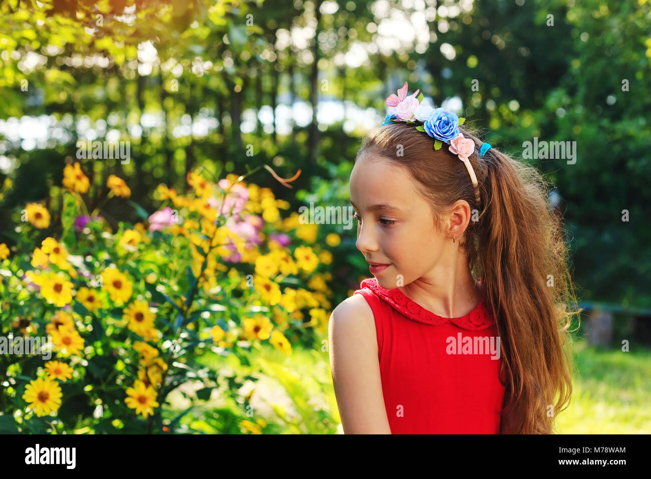 Carino teen ragazza è seduta e sognare presso il giardino in un caldo giorno d'estate e di sole Foto Stock