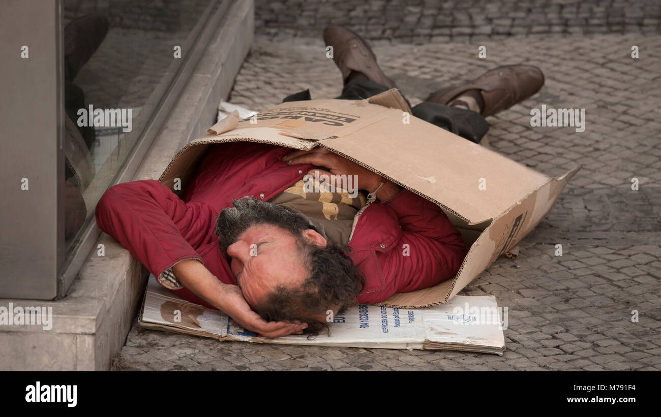 La persona senza dimora che dorme sul percorso in una scatola di cartone Foto Stock