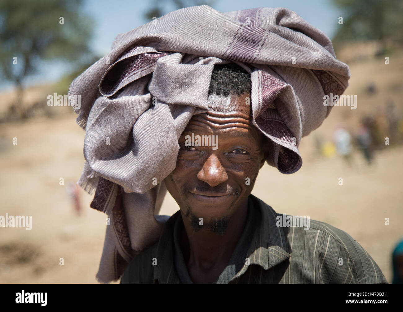Uomo che protegge dal sole cocente con una coperta su un giorno di mercato, Oromo, Sambate, Etiopia Foto Stock