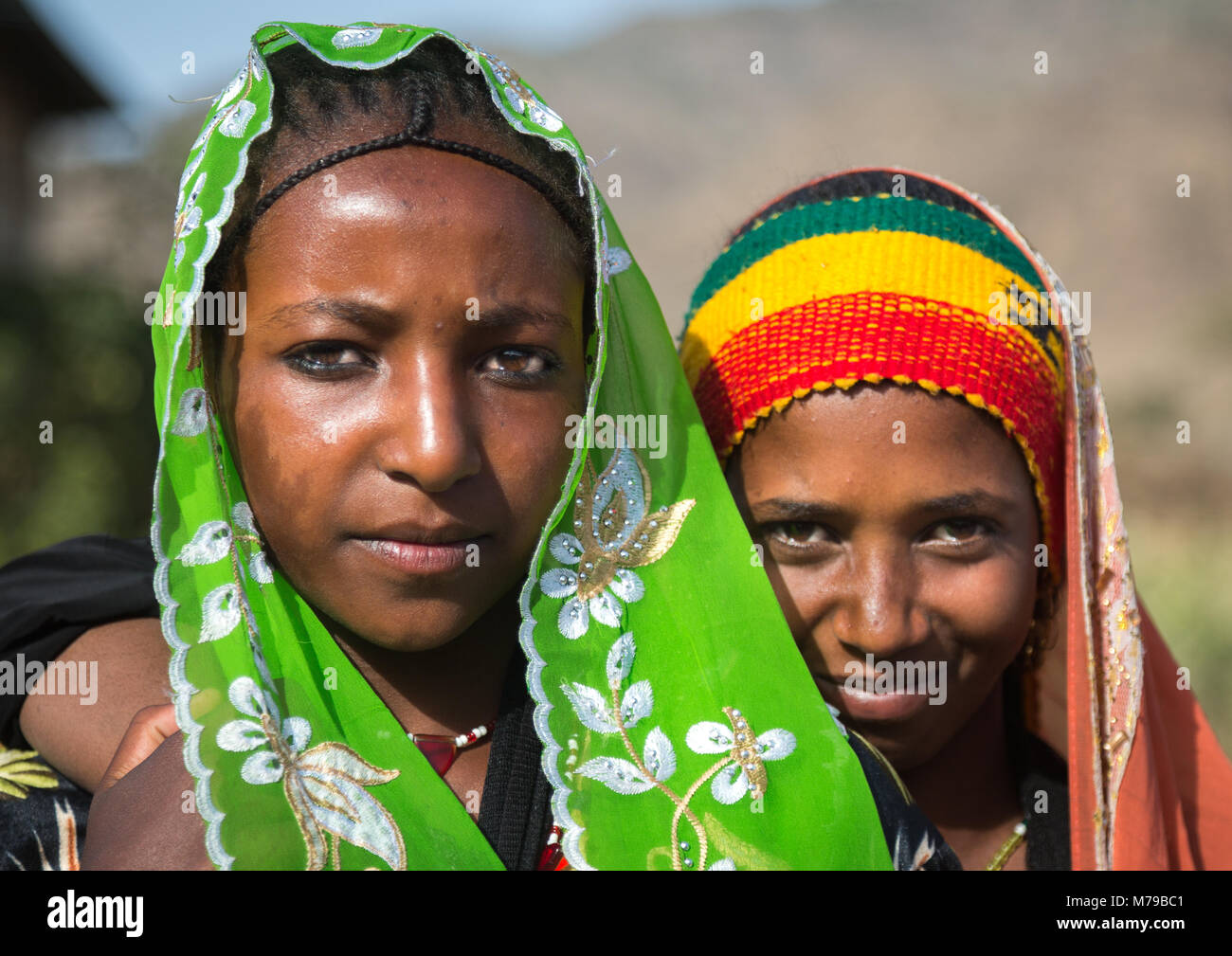 Ritratto di una ragazza di oromo indossando una fascia con i colori della bandiera etiope con il suo amico, Regione di Oromo, Sambate, Etiopia Foto Stock