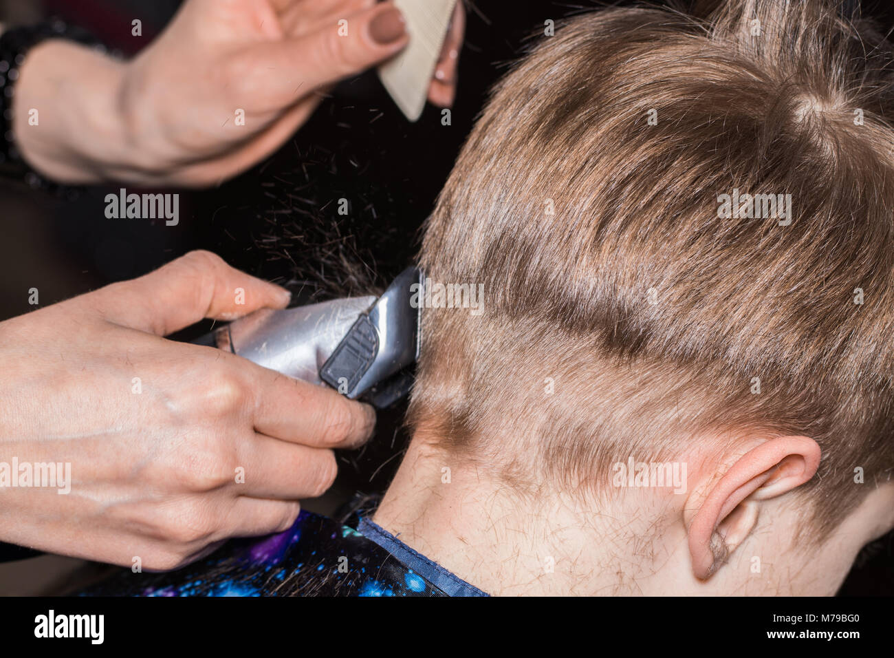 Vista laterale della cute little boy getting haircut dal parrucchiere al barbiere. Foto Stock