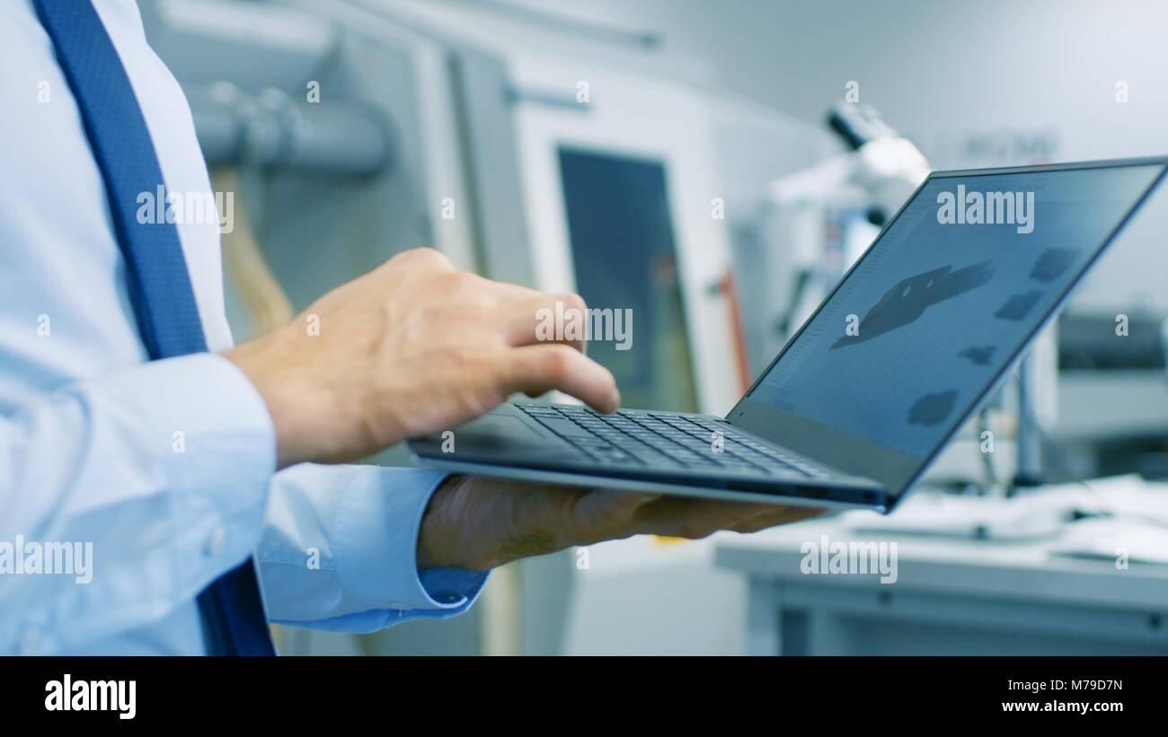 Close-up dell'Ingegnere Azienda portatile con CAD modello di componente sullo schermo. In background moderno equipaggiamento di fabbrica. Foto Stock