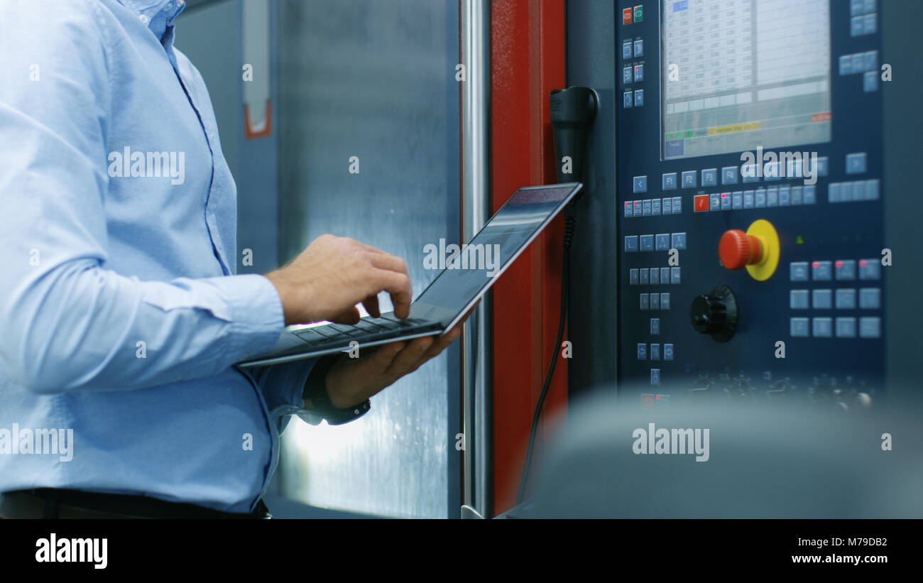 Il Chief Engineer/ operatore Programmi/ Set-up macchina CNC con il pannello di controllo. Egli lavora sulla moderna tecnologicamente avanzata di fabbrica. Foto Stock
