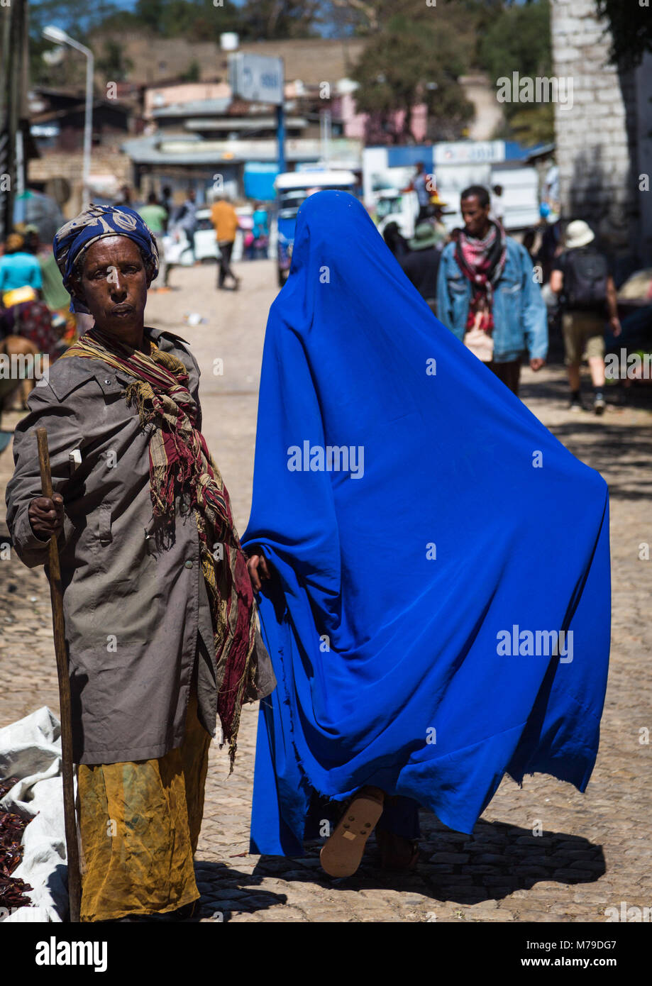 Donna con un blu brillante burqa lasciando la vecchia città mercato, Harari regione, Harar, Etiopia Foto Stock