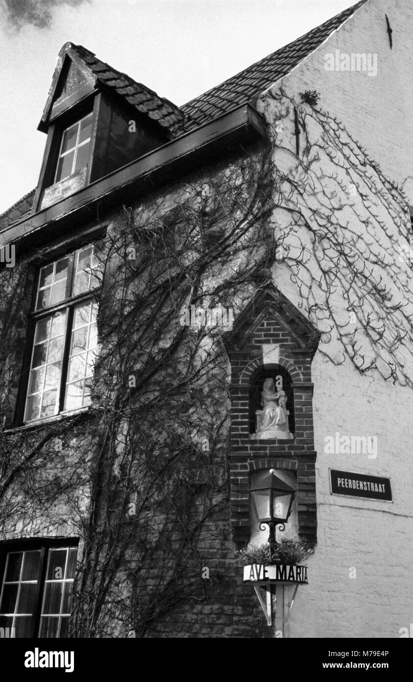 Peerdenstraat: una vecchia casa da sopra il ponte sul canale Groenerei in fondo Peerdenstraat, Brugge, Belgio: una Madonna e Bambino in una nicchia di mattoni. Film in bianco e nero fotografia Foto Stock