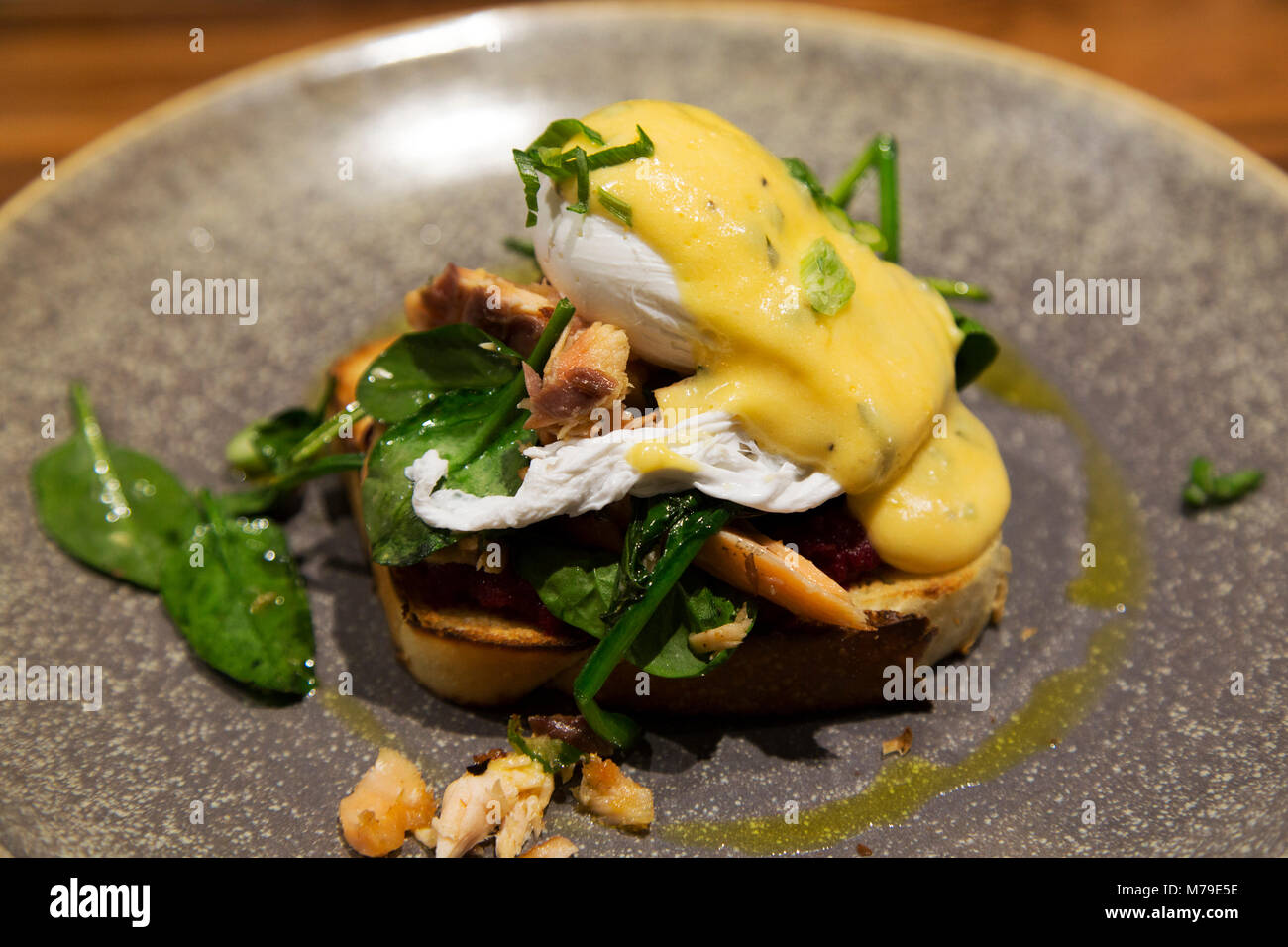 Salmone e Uovo affogato servita con verdure di stagione e tappoed con salsa olandese. Il piatto viene servito su toast a lievitazione naturale. Foto Stock