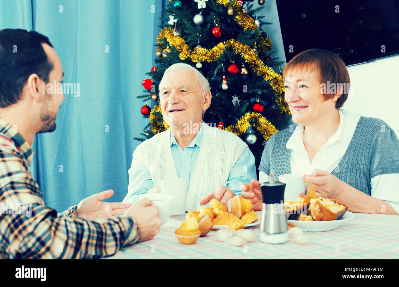 Sorridente madre e padre e figlio adulto trascorrere il Natale insieme a casa Foto Stock