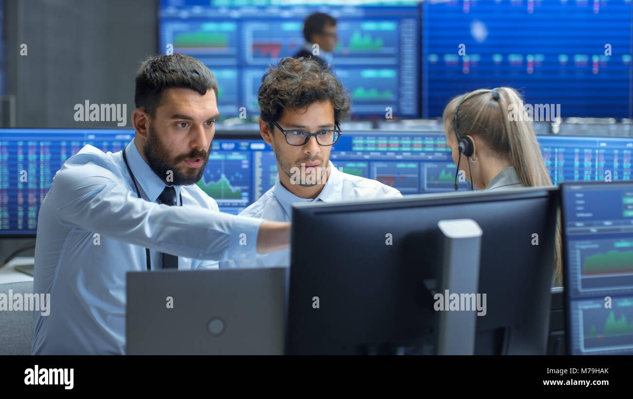 Broker Professionale Consulta Stock Exchange Trader presso la propria workstation. Team Multi-Ethnic a Stock Exchange Office è occupato di vendita e di Acquisto di scorte Foto Stock