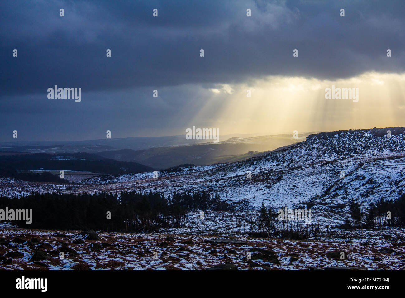 Raggi di sole proveniente attraverso le nubi in un giorno di neve, Burbage, Peak District Foto Stock