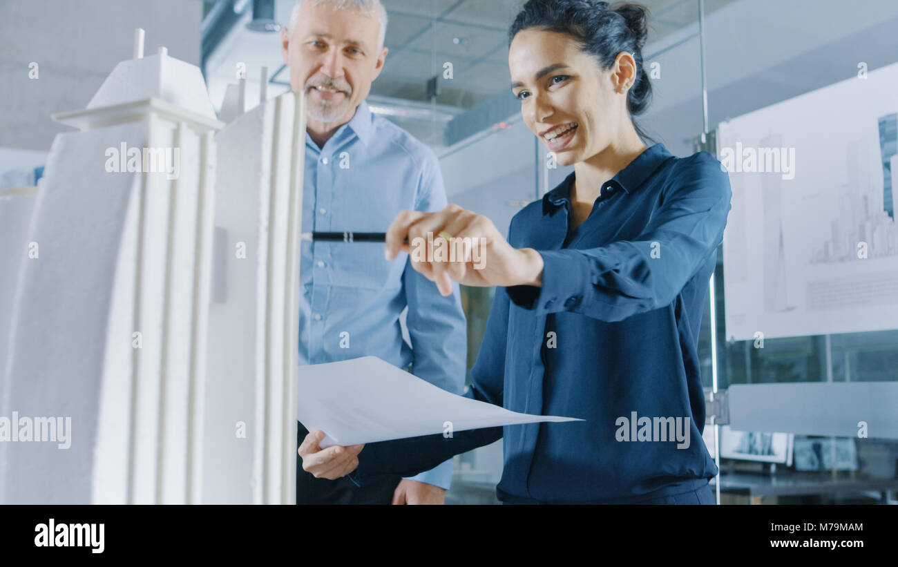 Due professionale maschio e femmina ingegneri architettonico lavorare con Blueprint e su un modello di edificio di design per la pianificazione urbana progetto. Foto Stock