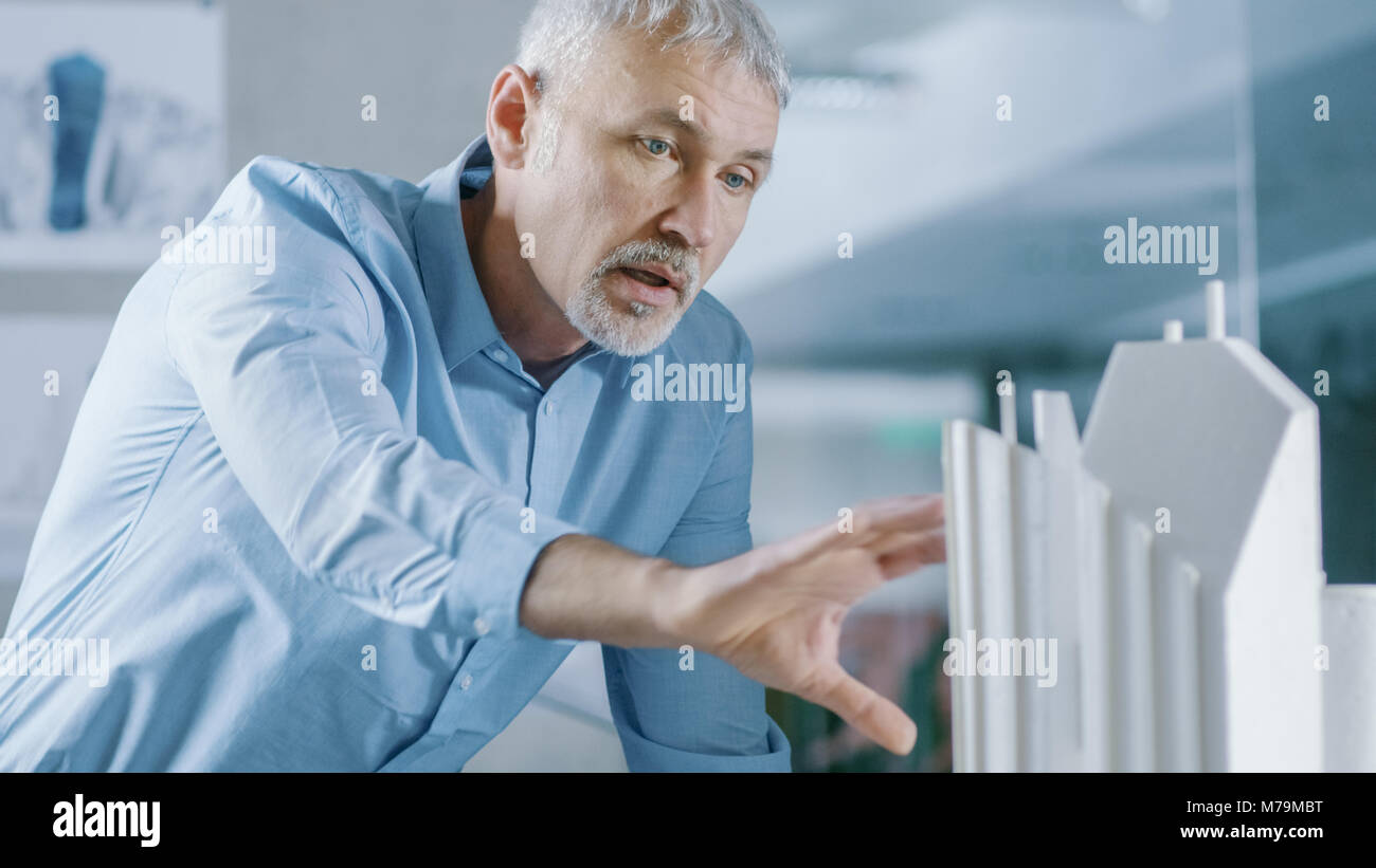 Maschio ingegnere senior e femmina progettista architettonico di lavoro su un modello di edificio di design per la pianificazione urbana progetto. Foto Stock